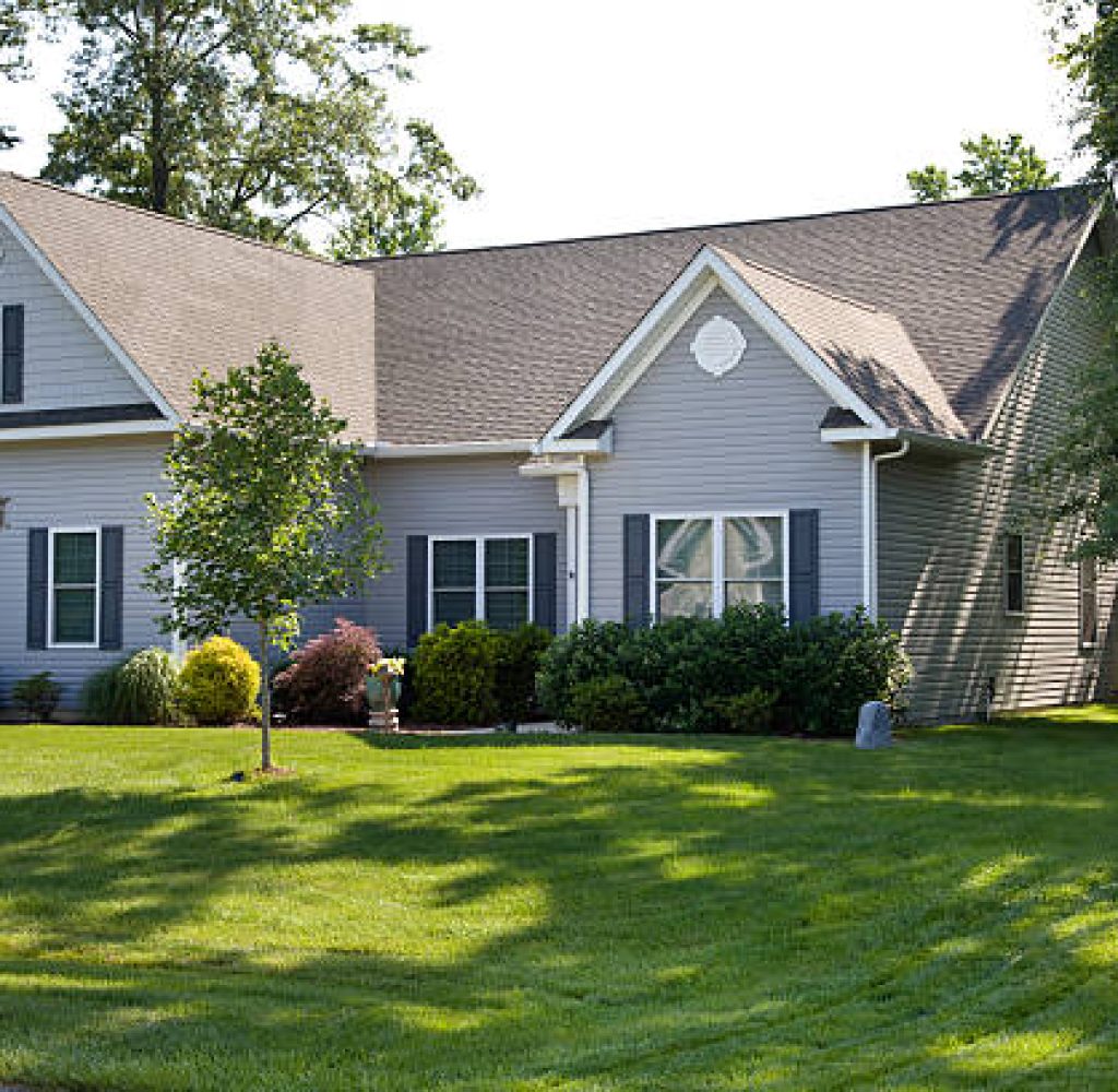 Front yard and suburban home with manicured lawn in the suburbs. Roofer installing roof shingles in Williamson County, TX home